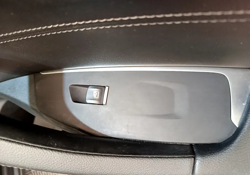 Gros plan sur le bouton de commande de lève-vitre côté conducteur dans l'intérieur noir du BMW X3 xDrive20d 2019.