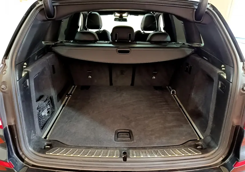 Coffre ouvert d'un BMW X3 noir 2019, vue arrière montrant l'espace de chargement et la tablette cache-bagages.