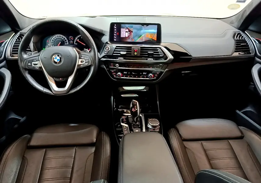 Intérieur noir de BMW X3 2019 vu de face, tableau de bord avec écran tactile 10,3 pouces et volant multifonctions.
