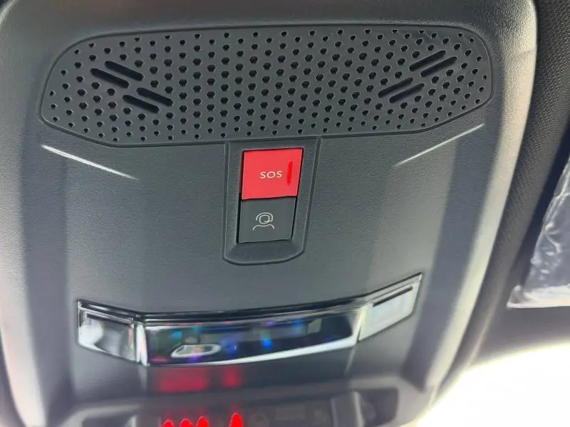 Vue rapprochée du plafonnier noir avec bouton SOS rouge et commande d’assistance dans un Peugeot 2008 bleu 2025.