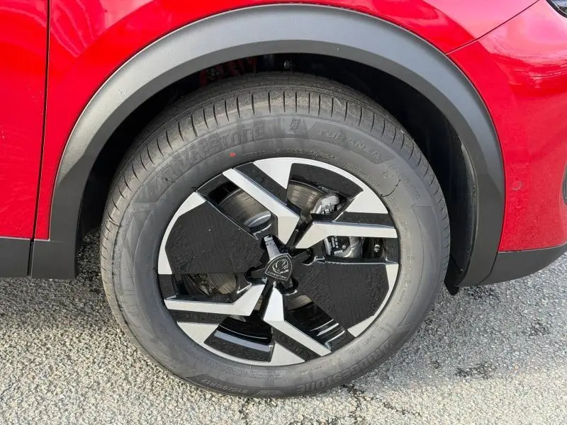 Gros plan sur la roue avant droite noire et argentée du Peugeot 2008 rouge, soulignant la jante alu au design moderne.