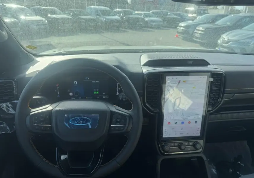 Vue intérieure centrée sur le volant multifonctions et l'écran tactile vertical du Ford Ranger gris 2025.