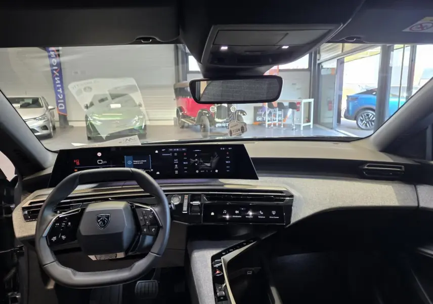 Vue intérieure du tableau de bord et volant cuir noir du Peugeot 3008 hybride 2025, avec écran panoramique incurvé.