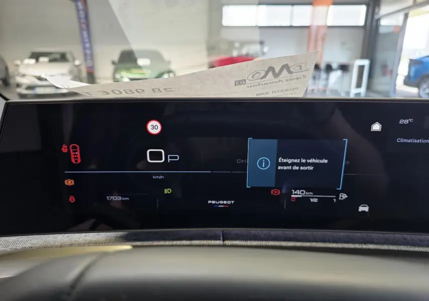 Vue rapprochée du tableau de bord numérique du Peugeot 3008 Hybrid 2025 avec affichage d'alerte et logo central.