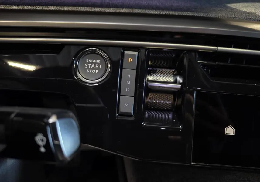 Gros plan sur la console centrale noire brillante du Peugeot 3008 2025 avec bouton start/stop et commandes de boîte auto.