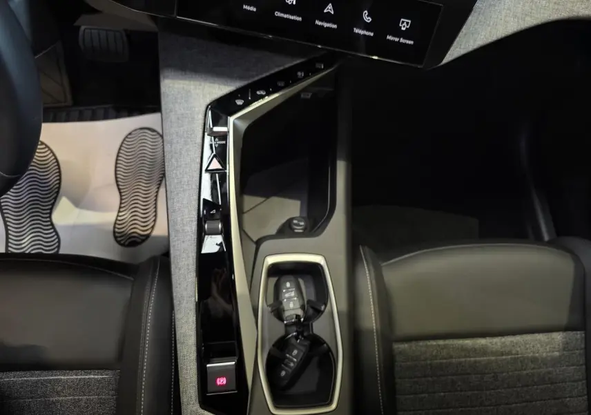 Vue rapprochée de la console centrale du Peugeot 3008 bleu clair 2025, avec clés et sellerie tissu gris foncé.