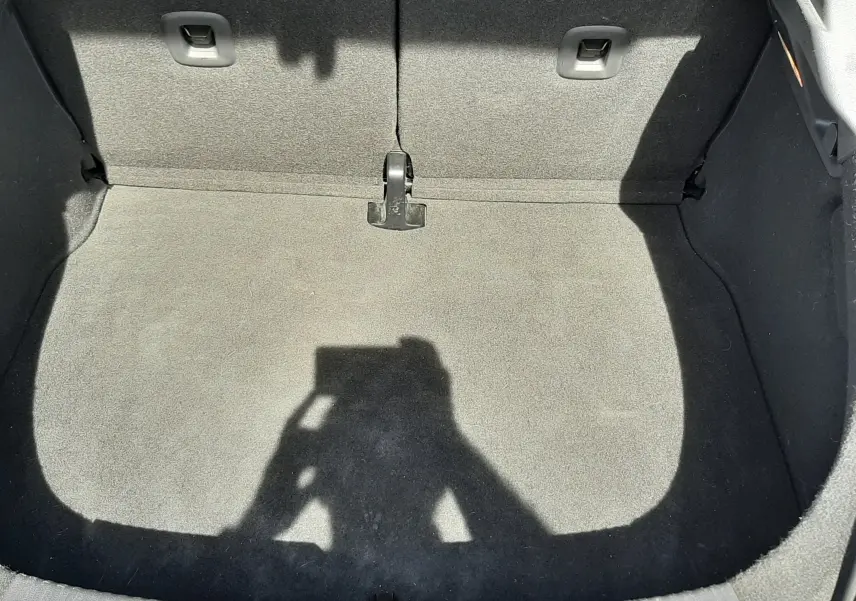 Vue plongeante sur le coffre vide tapissé de tissu gris clair du Volkswagen New Beetle noir de 2015.