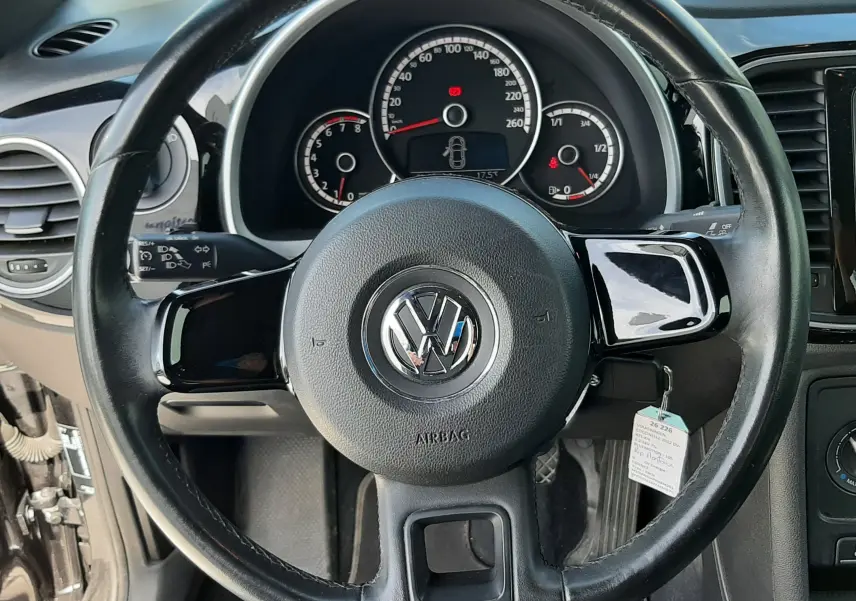 Vue frontale du volant noir de la Volkswagen New Beetle 2015, avec tableau de bord et compteurs visibles.