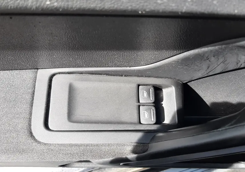 Gros plan sur les commandes électriques des vitres côté conducteur d’un Volkswagen New Beetle noir de 2015.