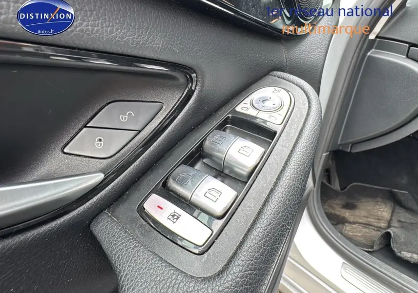 Gros plan sur les commandes de lève-vitres côté conducteur d'une Mercedes Classe C 180 d business gris alu de 2017.
