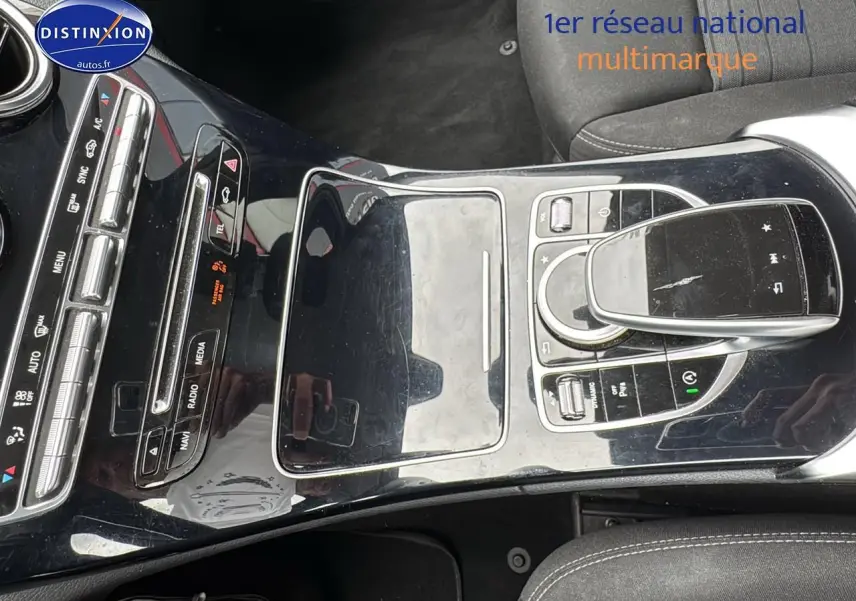 Vue rapprochée de la console centrale noire brillante de la Mercedes Classe C 180 d business 2017 avec commandes multimédia.