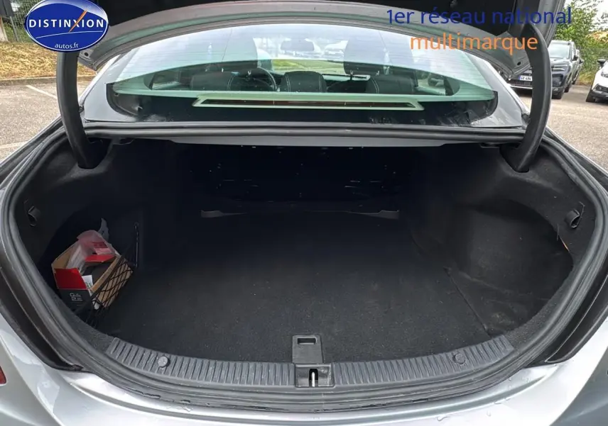Coffre ouvert vu de l'arrière d'une Mercedes Classe C 180 d business gris alu, montrant un espace de rangement vide.