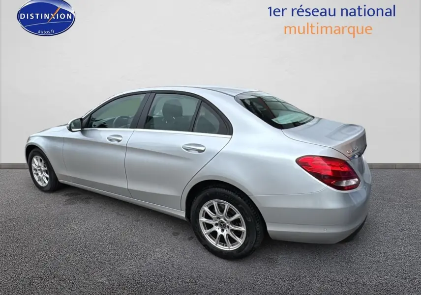 Mercedes Classe C 180 d business gris alu vue 3/4 arrière côté gauche, avec jantes alliage et feux arrière rouges.