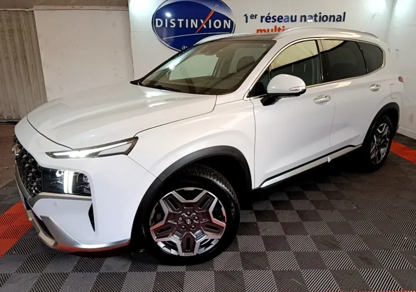 Vue 3/4 avant droit du Hyundai Santa Fe blanc avec phares LED allumés et jantes alliage distinctives.
