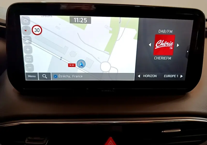 Écran tactile central du Hyundai Santa Fe hybride 2022 affichant navigation et radio Chérie FM sur tableau de bord noir.