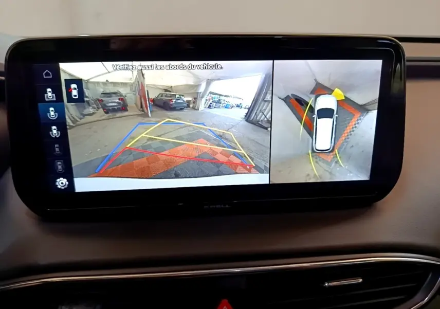 Écran tactile intérieur montrant la caméra de recul et vue à 360° du Hyundai Santa Fe blanc en stationnement.