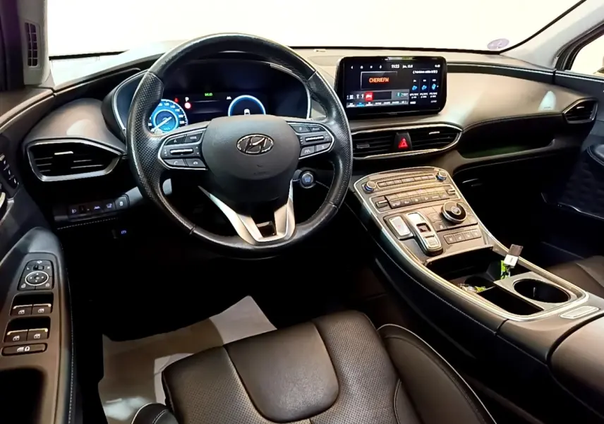 Vue intérieure du tableau de bord et volant cuir noir du Hyundai Santa Fe hybride 2022 avec écran tactile central.