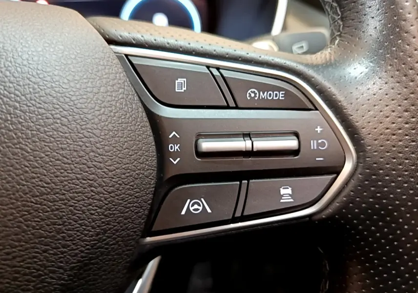 Gros plan sur les commandes noires du volant cuir du Hyundai Santa Fe hybride 2022, côté droit avec boutons multifonctions.