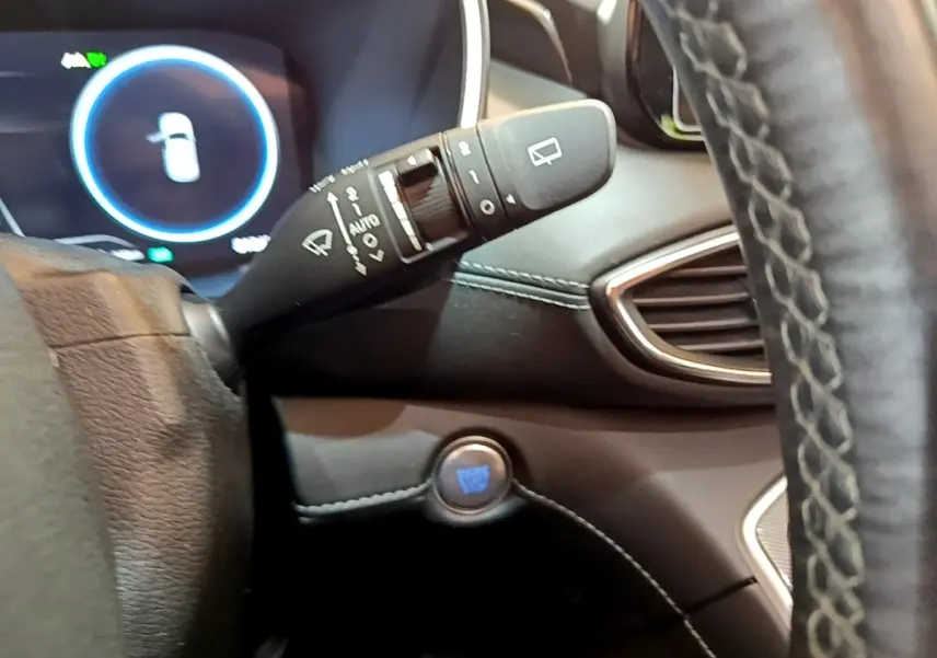Gros plan intérieur sur la commande d'essuie-glace et bouton démarrage bleu du Hyundai Santa Fe blanc 2022, côté gauche du volant.