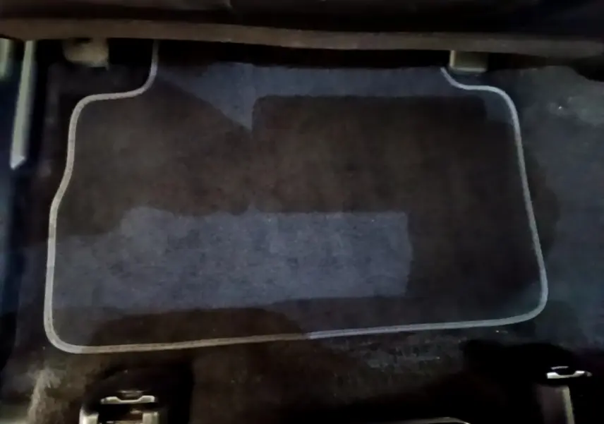 Tapis de sol noir avec bordure grise sous le siège arrière du Hyundai Santa Fe blanc hybride 2022.