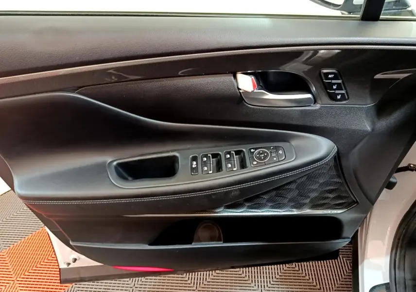 Panneau de porte côté conducteur noir avec commandes électriques et insert décoratif sur Hyundai Santa Fe blanc 2022.