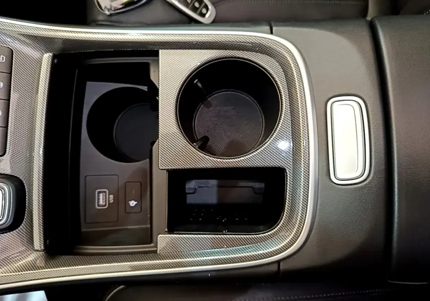 Gros plan sur la console centrale du Hyundai Santa Fe blanc 2022, avec porte-gobelets et prise USB visible.