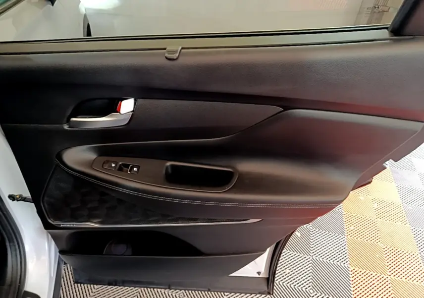 Gros plan sur la porte arrière gauche blanche du Hyundai Santa Fe 2022 avec garniture noire et commandes de fenêtre.