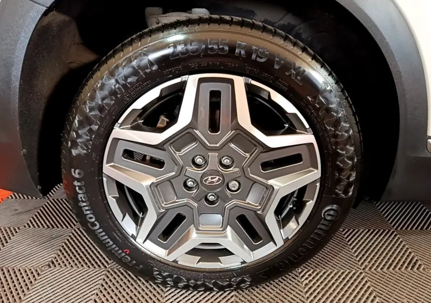 Gros plan sur la roue avant droite du Hyundai Santa Fe blanc, jante alliage à design étoilé et pneu Continental.