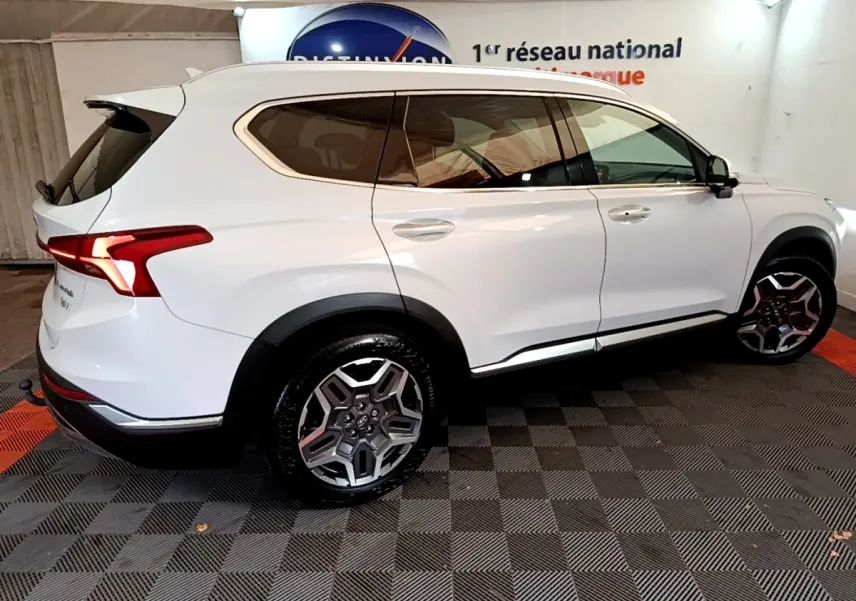 Vue latérale droite du Hyundai Santa Fe blanc 2022, soulignant ses jantes alliage et ses vitres teintées.