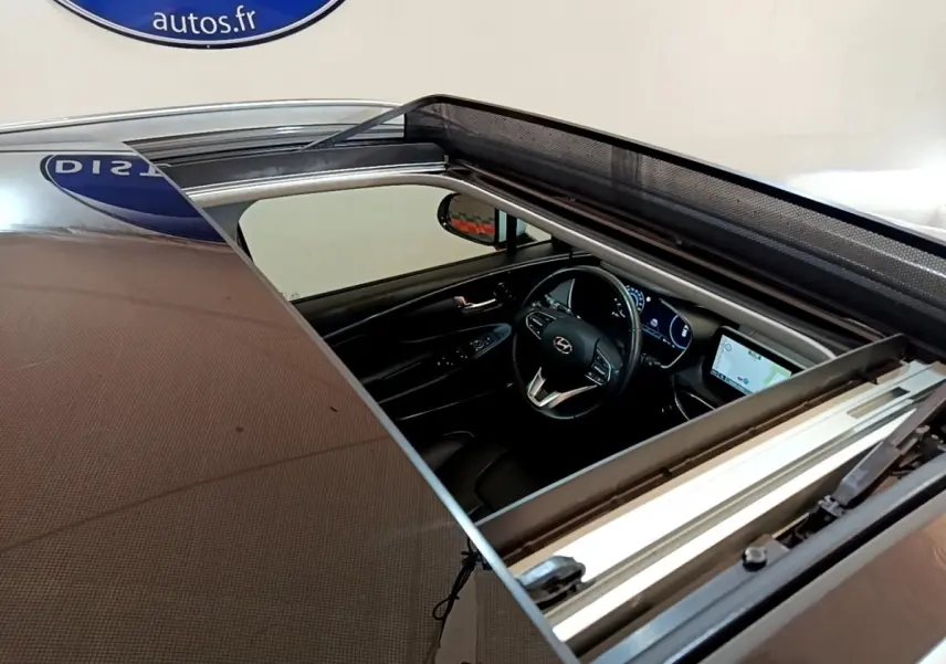 Vue plongeante sur l'intérieur noir du Hyundai Santa Fe 2022 via toit ouvrant panoramique ouvert.