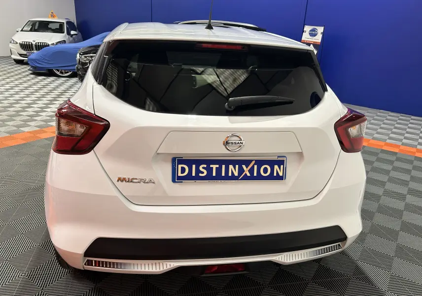 Vue arrière d'une Nissan Micra blanche 2021 en intérieur, avec plaque Distinxion et feux arrière distinctifs.