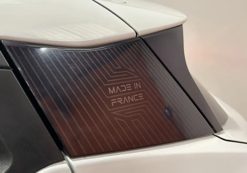 Gros plan sur la vitre arrière droite blanche de la Nissan Micra 100ch avec l'inscription "Made in France" visible.