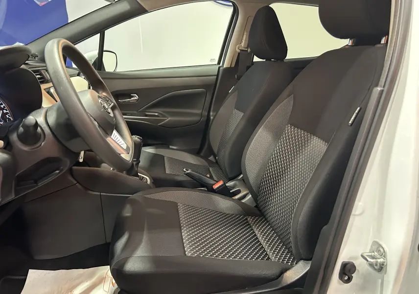 Vue intérieure côté conducteur de la Nissan Micra blanche 2021, sièges tissu noir avec motifs géométriques.