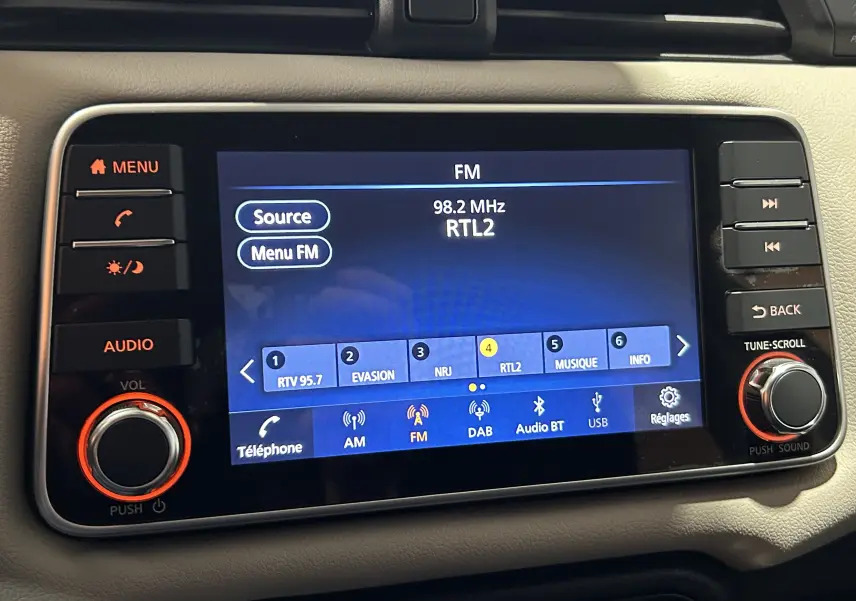 Écran tactile central de la Nissan Micra 2021 affichant la radio FM sur fond noir avec boutons de contrôle autour.