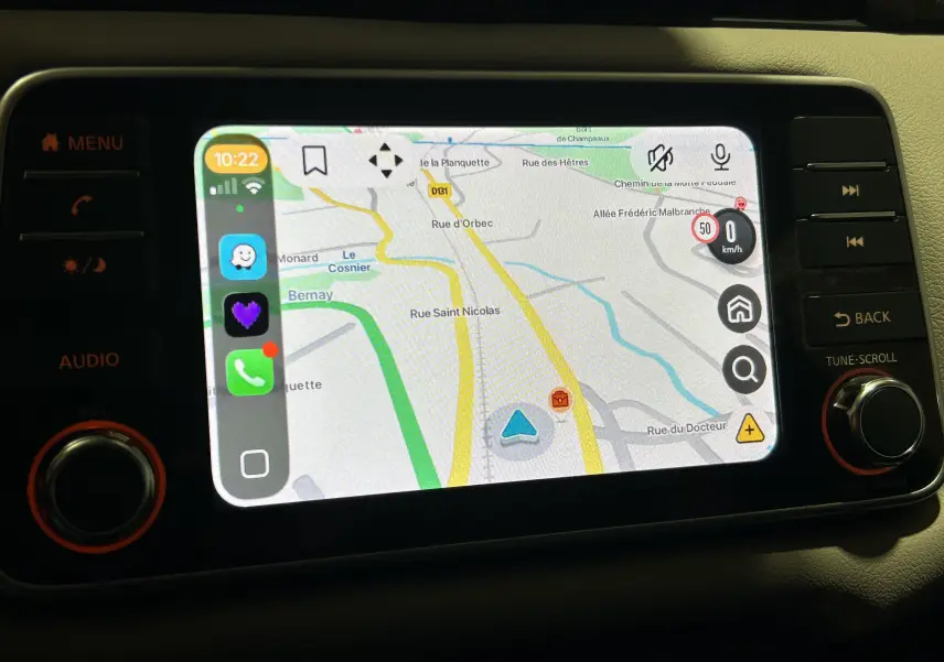 Écran tactile central de la Nissan Micra 2021 affichant la navigation avec interface CarPlay, boutons et molette autour.