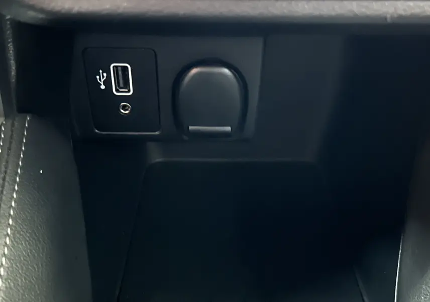 Gros plan sur la prise USB et allume-cigare dans l’espace de rangement central intérieur d’une Nissan Micra blanche.