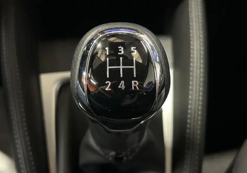 Gros plan sur le levier de vitesses manuel noir et chrome de la Nissan Micra blanche de 2021, intérieur sombre.