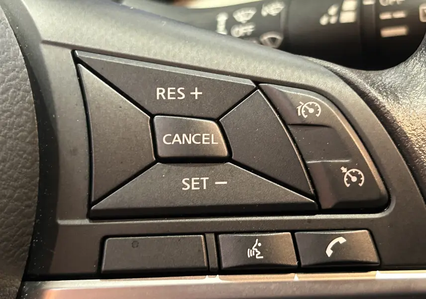 Gros plan sur les commandes de régulateur de vitesse et téléphone au volant d'une Nissan Micra blanche de 2021.