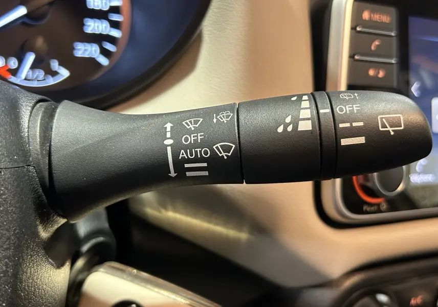 Gros plan sur la commande d’essuie-glace à gauche du volant dans l’habitacle beige d’une Nissan Micra blanche de 2021.