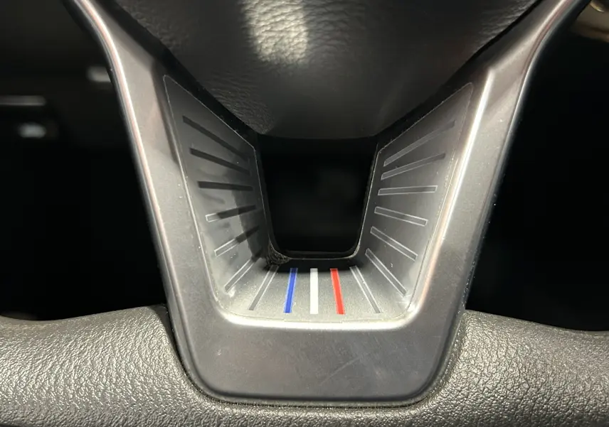 Détail du volant de la Nissan Micra 2021 avec insert tricolore bleu, blanc, rouge au centre.