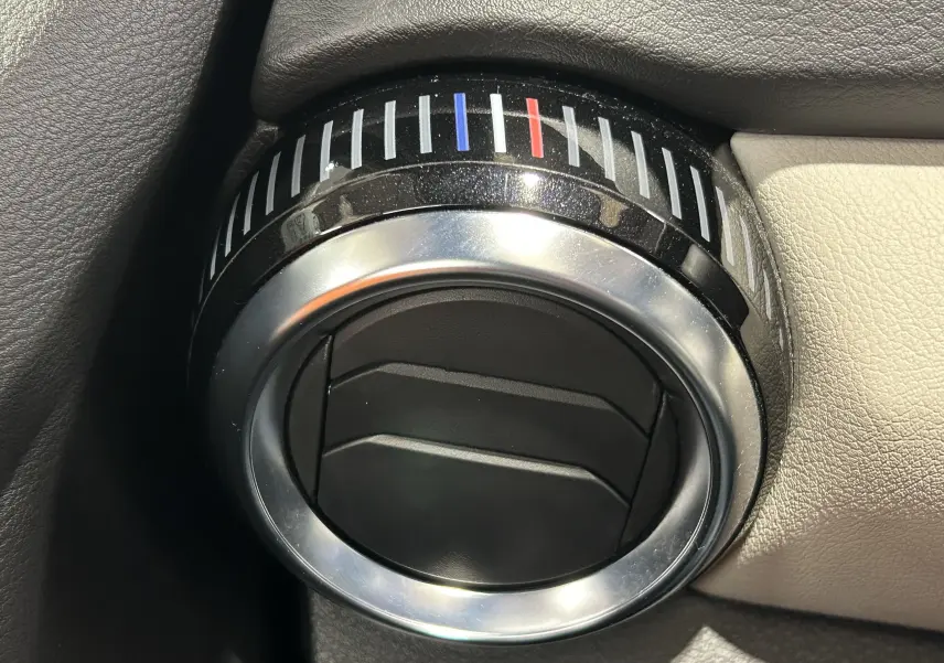 Gros plan sur la commande de réglage de la climatisation noire et argentée dans l’habitacle d’une Nissan Micra blanche.