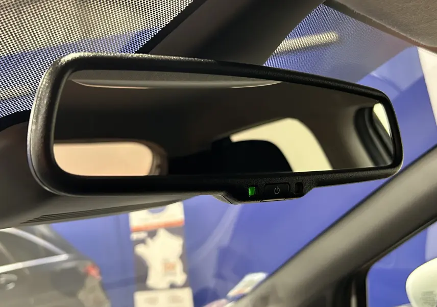 Rétroviseur intérieur avec témoin vert allumé, vue rapprochée de l'habitacle d'une Nissan Micra blanche.