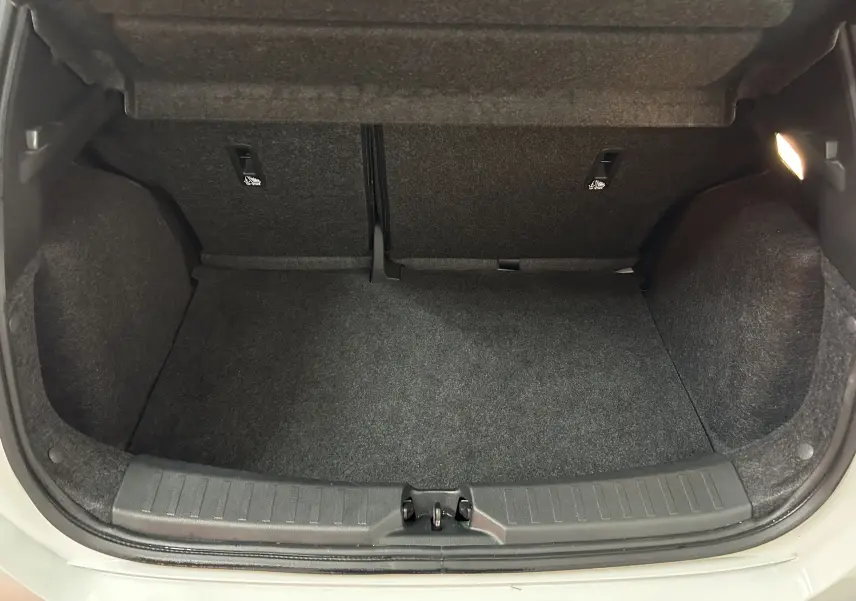 Coffre ouvert vu de face d'une Nissan Micra blanche, montrant un espace de rangement propre et vide.