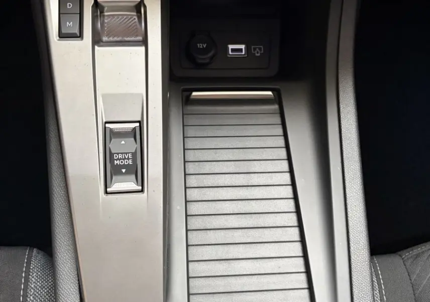 Vue rapprochée de la console centrale noire de la Peugeot 308 2024 avec bouton start, sélecteur boîte auto et prise 12V.
