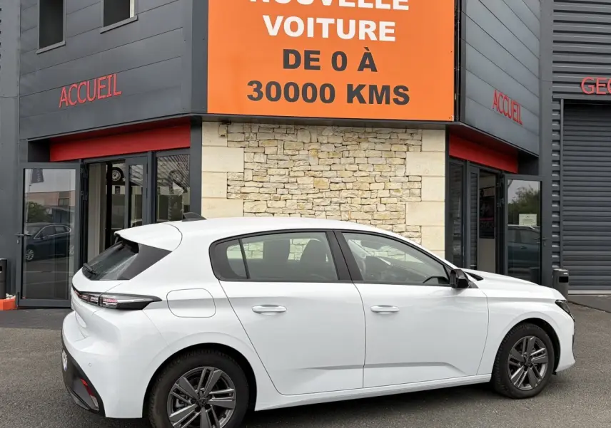Peugeot 308 blanche vue de profil côté droit, avec rétroviseurs ton caisse et jantes alliage foncé.