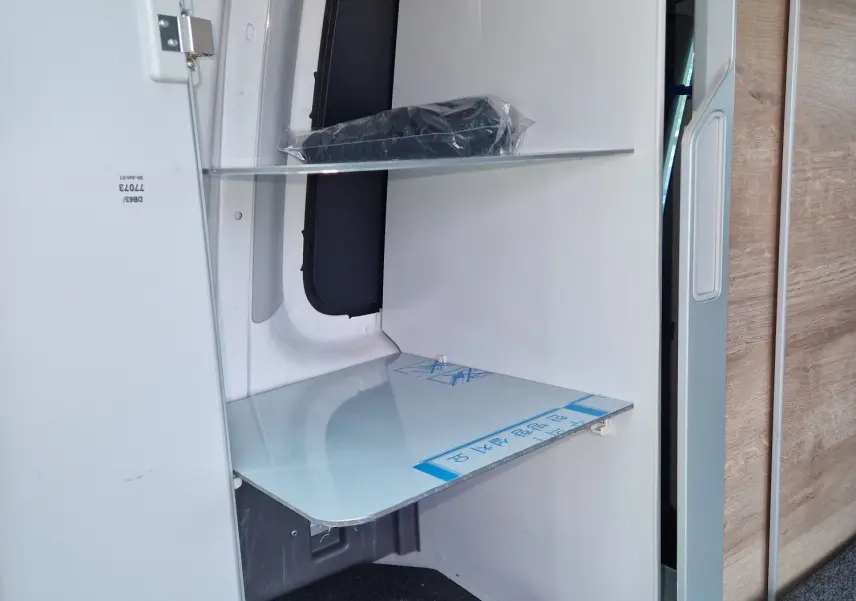 Intérieur du Volkswagen California 2021 Cooper bronze montrant un rangement avec douchette escamotable et étagères blanches.