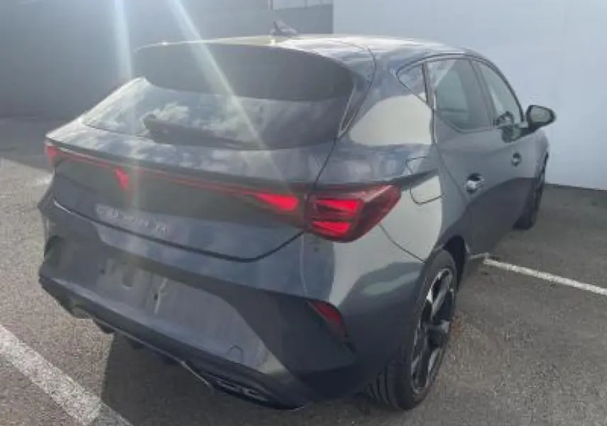 Vue 3/4 arrière droite d'une CUPRA Leon 2025 gris magnetic metal avec feux arrière Tri-LED et double sortie d'échappement noire.