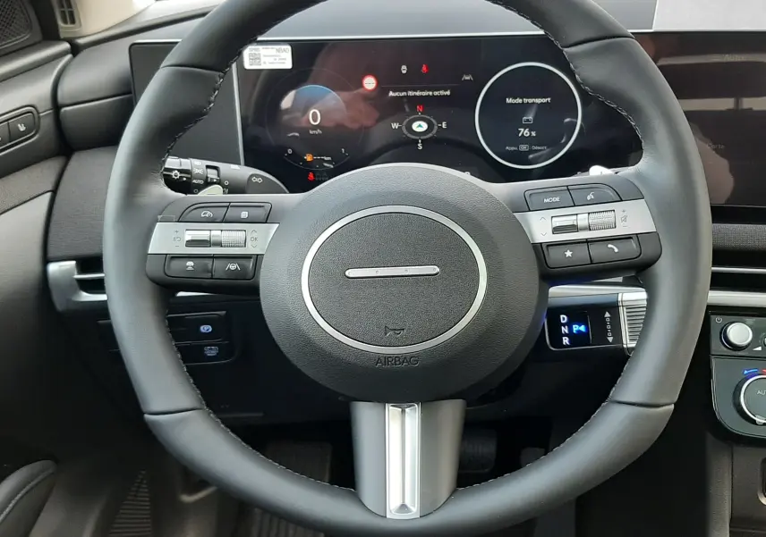 Vue frontale du volant noir et du tableau de bord numérique du Hyundai Tucson 2025 hybride en intérieur.