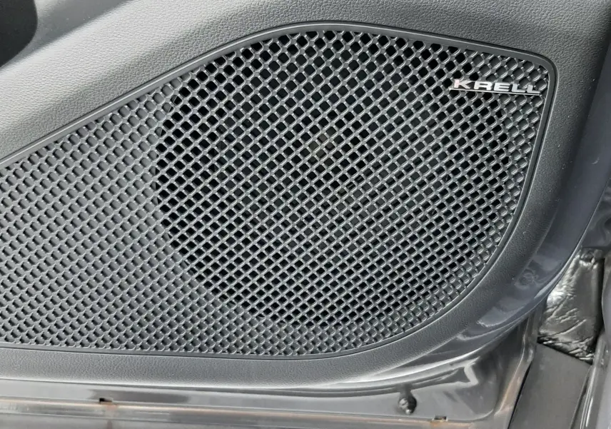 Gros plan sur le haut-parleur Krell intégré à la porte intérieure noire du Hyundai Tucson 2025 Ecotronic Grey hybride
