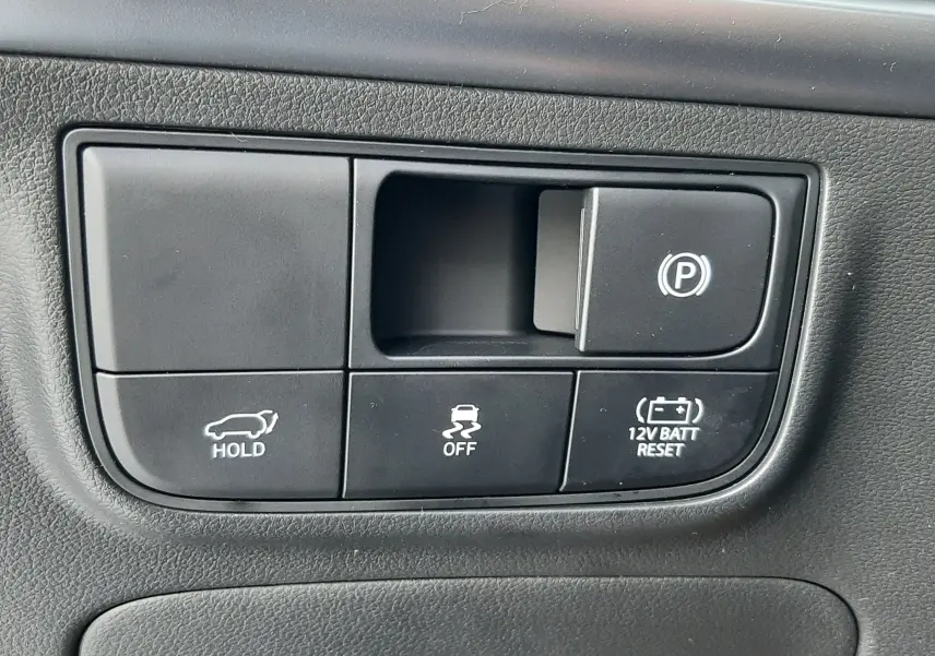 Gros plan sur les commandes noires du tableau de bord du Hyundai Tucson 2025, boutons de parking, traction et reset batterie.